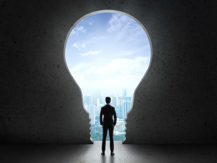 A person standing in a keyhole-shaped passage looking towards clarity and light